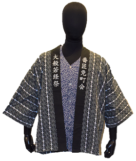 グレーに白の縦の線の入った模様が入り、黒の襟に「大般若経祭 番匠免町会」と文字の入った祭礼衣装を前から写した写