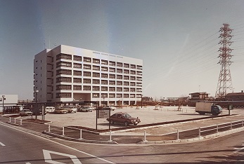 昭和58年(1983年)に撮影された、竣工したばかりの7階建ての三郷市役所とその手前にある広い駐車場の写真