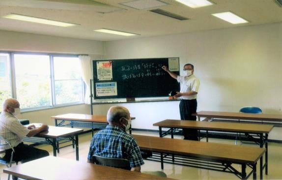 黒板を使って作者の想いを解説している講師と、学んでいる参加者の方々の写真