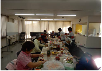 いくつかくっつけて置かれた机に飲み物や食べ物が置かれ10名程が団らんしている懇親会の様子の写真