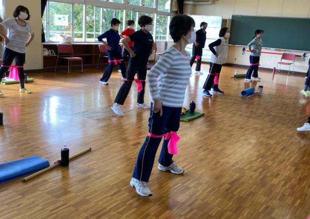 たくさんのサークルメンバーが両ひざの上で紐を結び、腰に手を当てて左側に体重を掛けている写真
