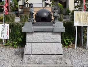 右脇侍に虚空蔵菩薩、左脇侍に慈母観音菩薩を配した中央に接地部分がくりぬかれている黒光りした球体が設置されたうなぎ供養塔の写真