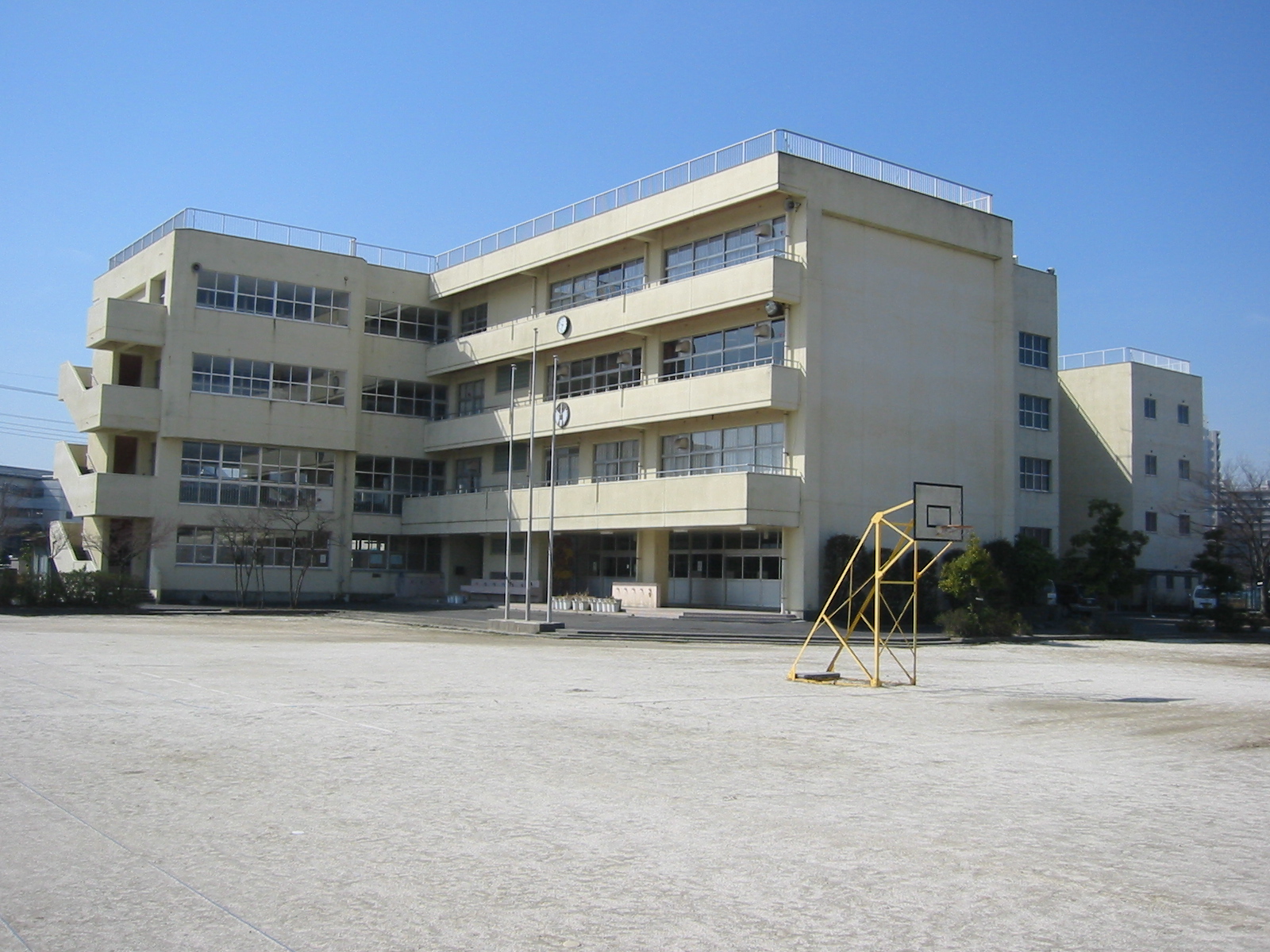建物前にはバスケットゴールが置かれている広々とした広場がある白い外壁の4階建ての建物の北公民館の外観写真