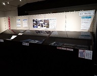 ガラスケースに展示物が並んでおり、壁には写真や資料の説明が提示されている館内の写真
