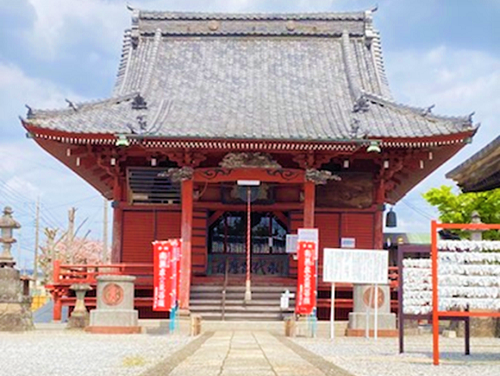 青空の下、参道から繋がる入母屋造桟瓦葺と朱色壁の延命院虚空蔵堂の外観写真
