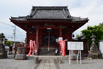 両端に石灯篭が設置され中央の壁や柱が赤色に塗られた延命院虚空蔵堂の建物の写真
