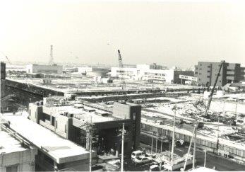 平成2年(1990年)に上空から撮影された、いくつものクレーン車が広い土地で工事をしている土地開発途中のインターチェンジ方面のモノクロ写真