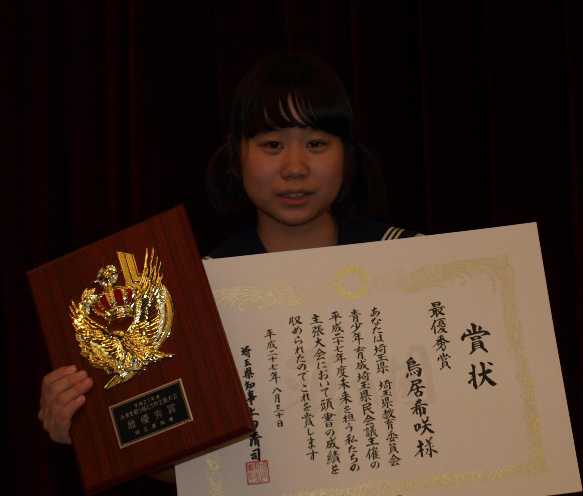 最優秀賞の盾と賞状を両手に持ち、笑顔の早稲田中 鳥居希咲さんの写真