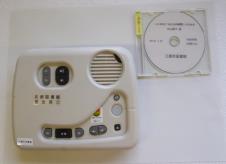 ケースに入ったCDと、様々なボタンが搭載された専用の再生機の装置が並んでいる写真