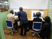 関係者のサポートを受けながらパソコンを操作している様子の2人の来館者を後ろから撮った写真