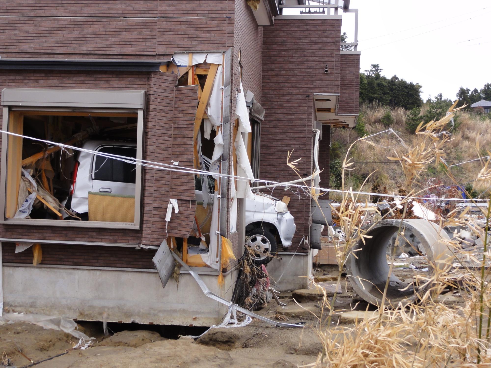 家の中に車が入り、建物が破損された広野町の災害現場の写真