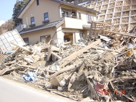 倒壊した2階建ての家の手前は瓦礫でいっぱいの陸前高田市の様子の写真