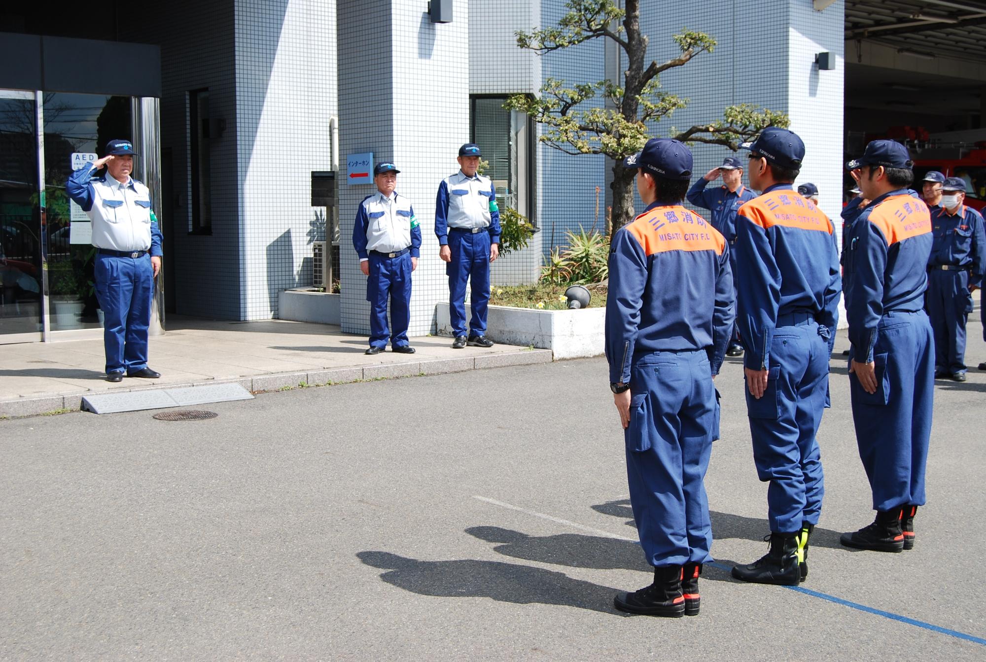 隊員3名が横に並び、隊員に向かって敬礼している写真