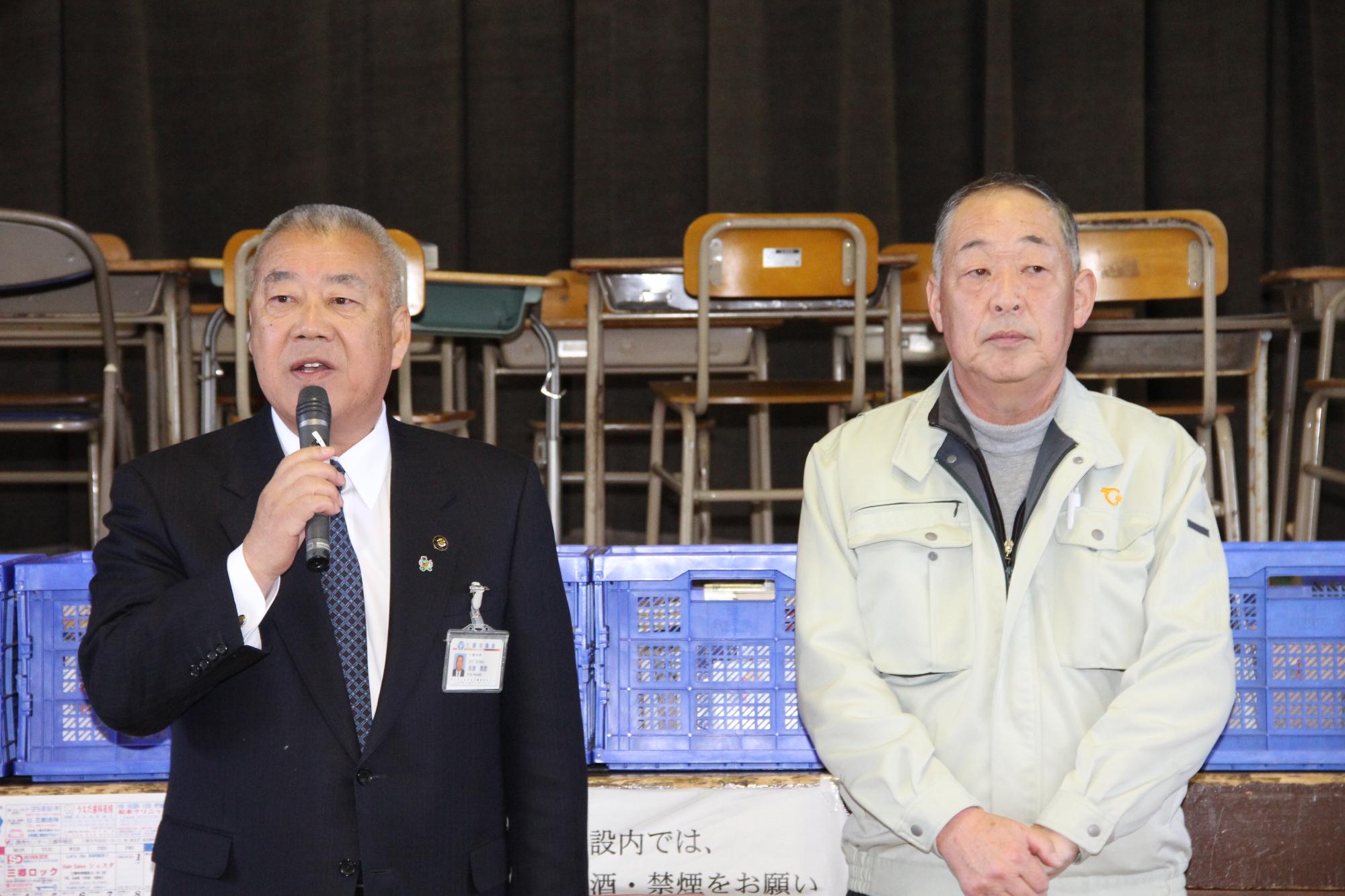 三郷市木津市長がマイクで話をしており、横に山田基星広野町長が並んで立っている写真
