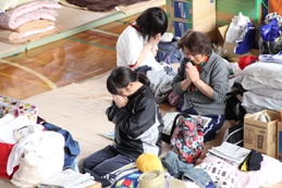 瑞沼市民センターに避難された方々が、正座をして手を合わせ、黙とうをしている写真