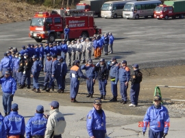 消防車が後ろで待機し、大勢の派遣部隊の方々が集まっている写真