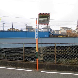 左右確認の注意版が設置された、フェンス前にある道路反射鏡の写真