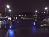 3名の夜間パトロール隊員が駐車場で駐留警戒をしている写真