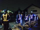 4名の夜間パトロール隊員が自転車の横に立ち、敬礼をする写真