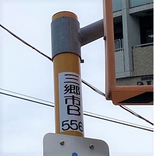 市の道路反射鏡に三郷市B556と記載のある管理札が貼られた写真