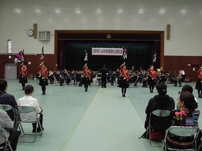 警察音楽隊の方々と6名のカラーガードの方々がパフォーマンスを披露している様子の写真