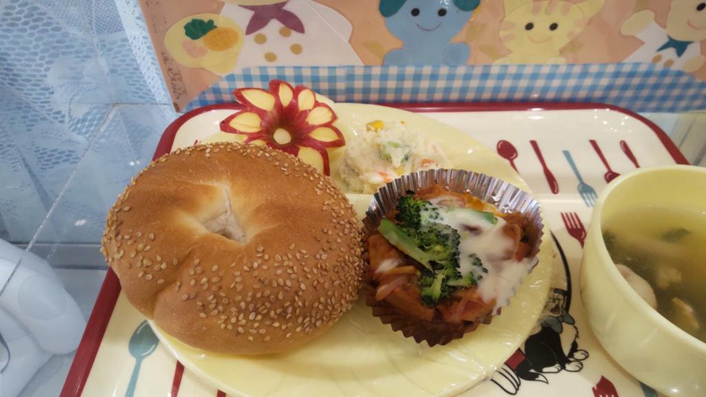 ギリシャパンクルーリ、スズカキアのクリーム焼き、タラモサラタ、みさと小松菜のスープ、皮で花柄になるようにカットされたりんごが盛り付けられた公立保育所で提供されたギリシャ給食の写真