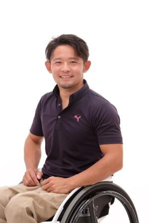 紺色のシャツを着て車いすに座っている花岡伸和氏の写真
