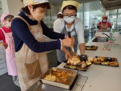 三角巾にエプロンを着用した女性が食材をプレートに盛り付けている様子の写真