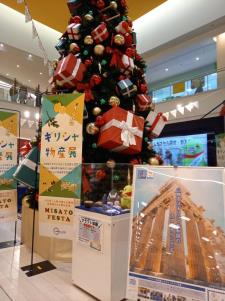 大きなクリスマスツリーの前にギリシャ物産展ののぼり旗やパネルが展示されえいる写真