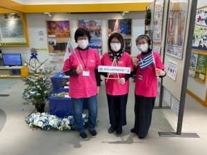 3名のお揃いのピンク色のシャツを着用した女性スタッフが横一列に並んでいる写真