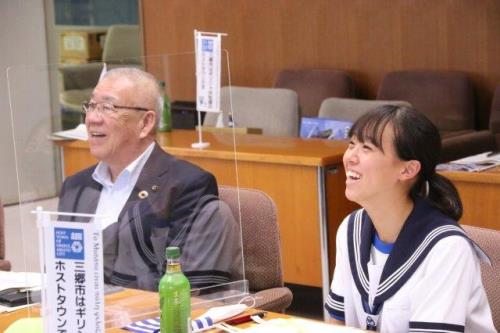 木津市長と彦成中学校3年の近藤さんが横一列に並んで座り選手たちと笑顔で交流を行っている様子の写真