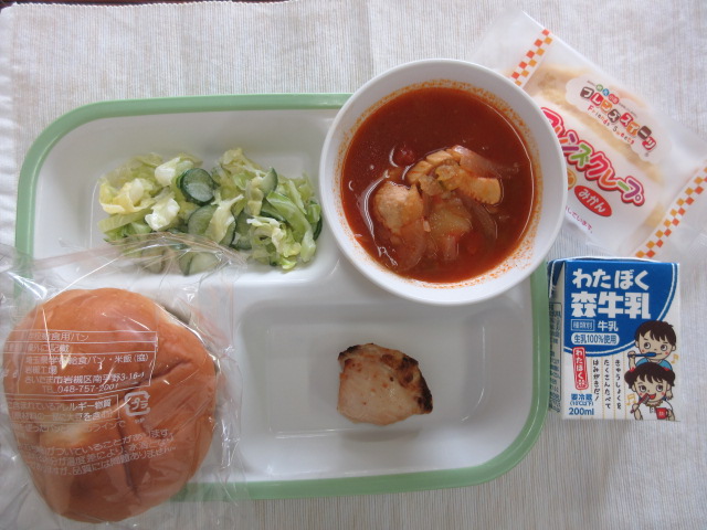 子供パン、スズカキア、鶏肉のスブラキ風焼き、グリーンサラダが盛り付けられ、みかんクレープと牛乳が添えられた小学校で提供されたギリシャ給食の写真