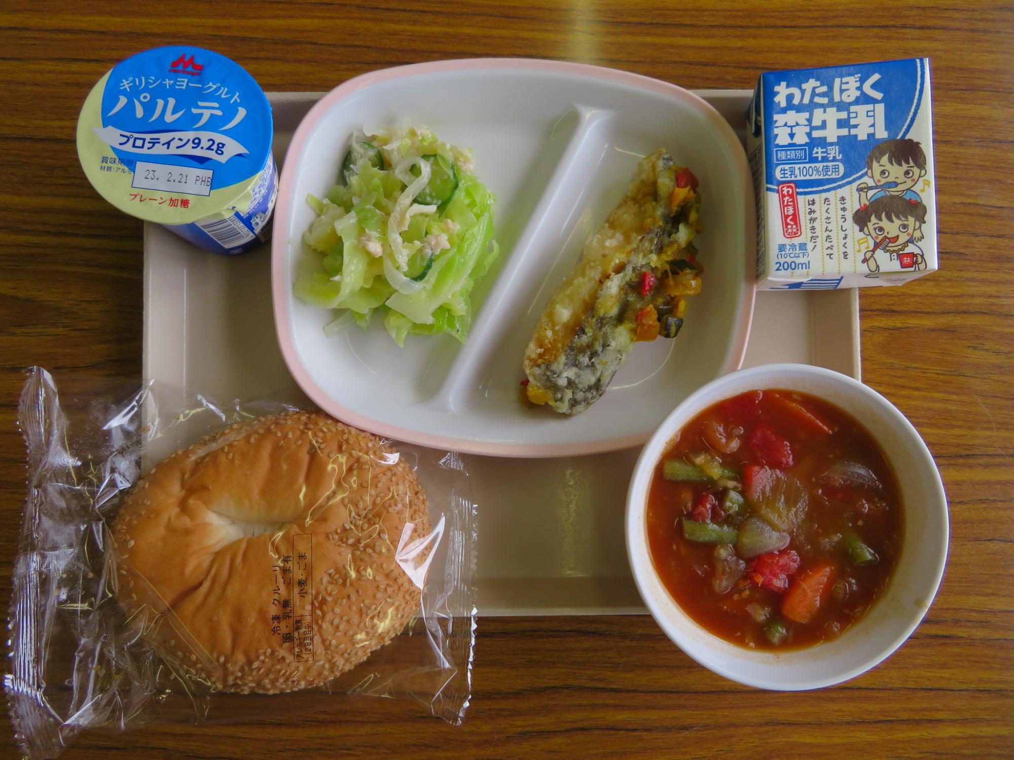 ギリシャパンクルーリ、ファソラーダ (いんげん豆のスープ)、白身魚のカレーマリネ、チキンサラダが盛り付けられ、ギリシャヨーグルト、牛乳が添えられた中学校で提供されたギリシャ給食の写真