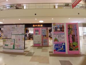 商業施設の広場に設置された掲示板に受賞作品が展示されている写真