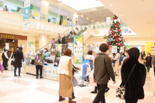 大きなクリスマスツリーが設置されているギリシャ物産展に沢山のお客さんが来店している写真