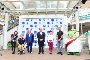 市長を中央に三郷市マスコットキャラクターかいちゃんとトークショーのゲストのアスリートの方々が横一列に並んでいる記念写真