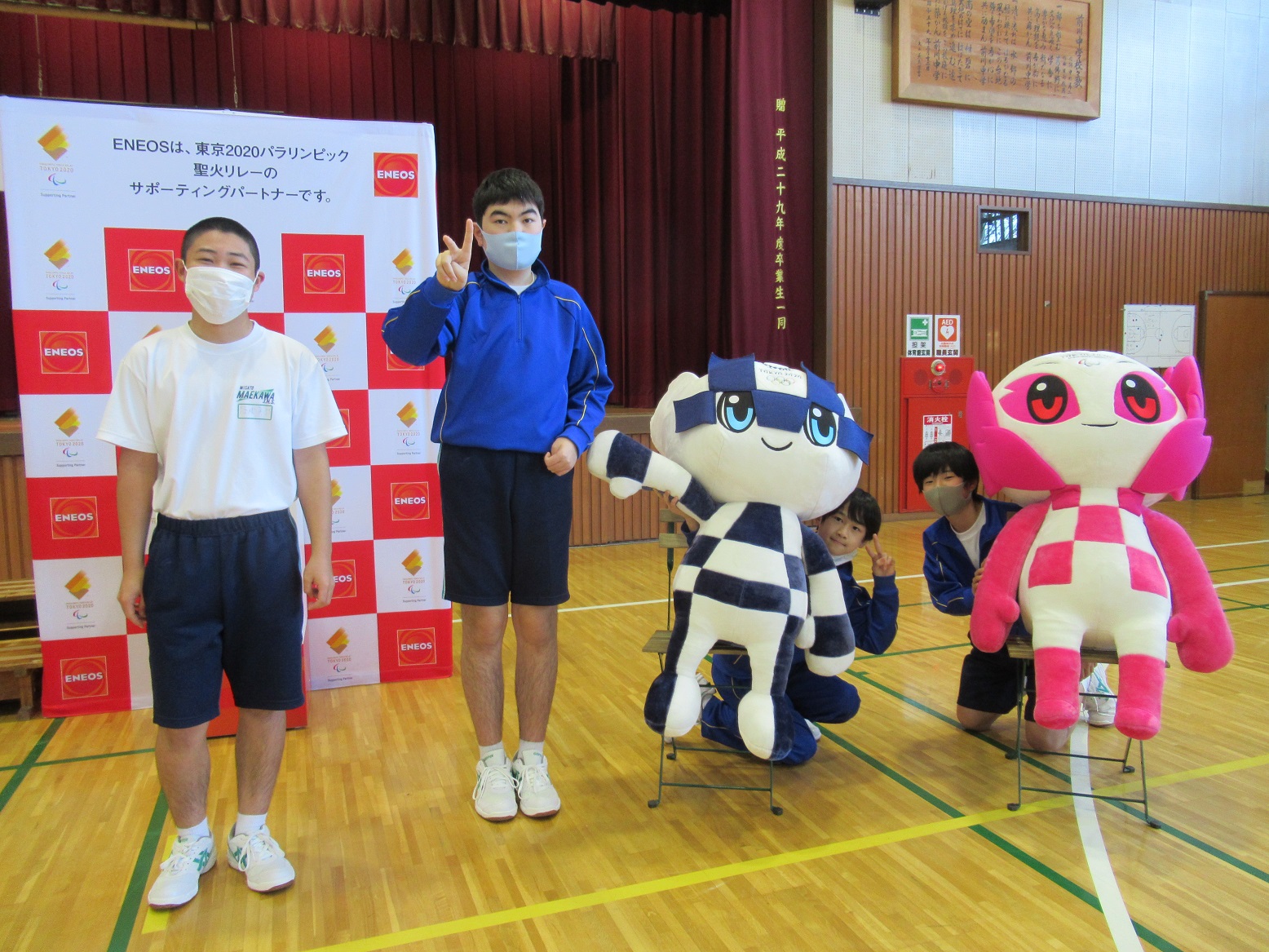 青い学校ジャージや、体育服を着た4人の男子学生がミライトワとソメイティと一緒に記念撮影をしている写真