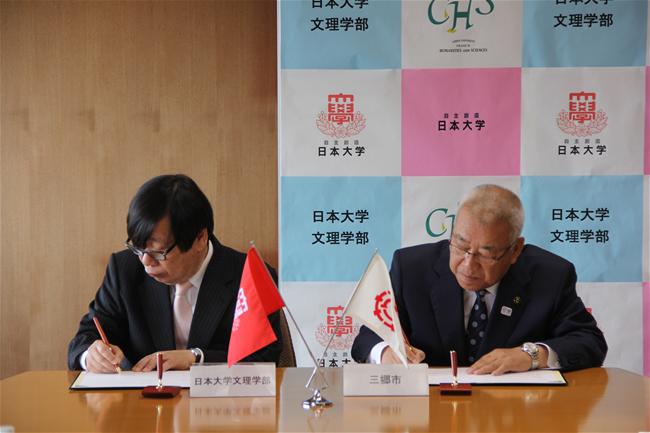 木津雅晟市長と加藤日本大学文理学部長が協定書にサインをしている写真