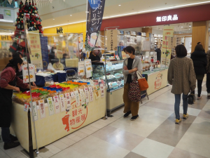 プリンなどの特産品のお菓子が販売されているブースを覗いているお客さんの写真