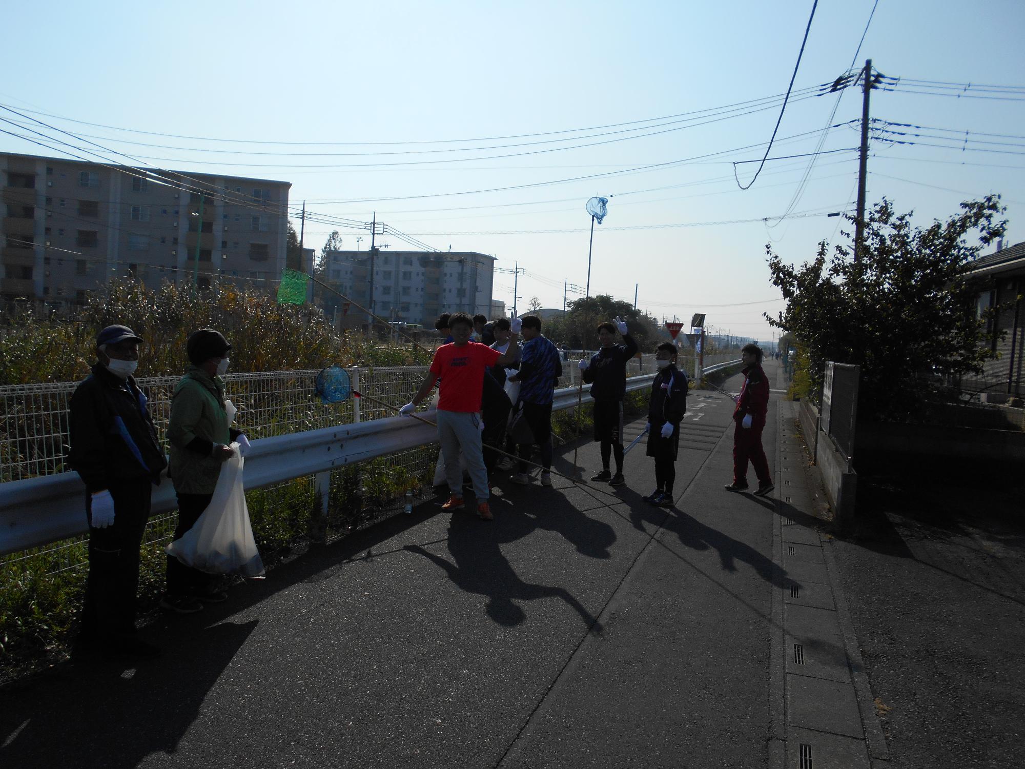 川沿いで浮遊ゴミをすくうための網を持っている人達の写真