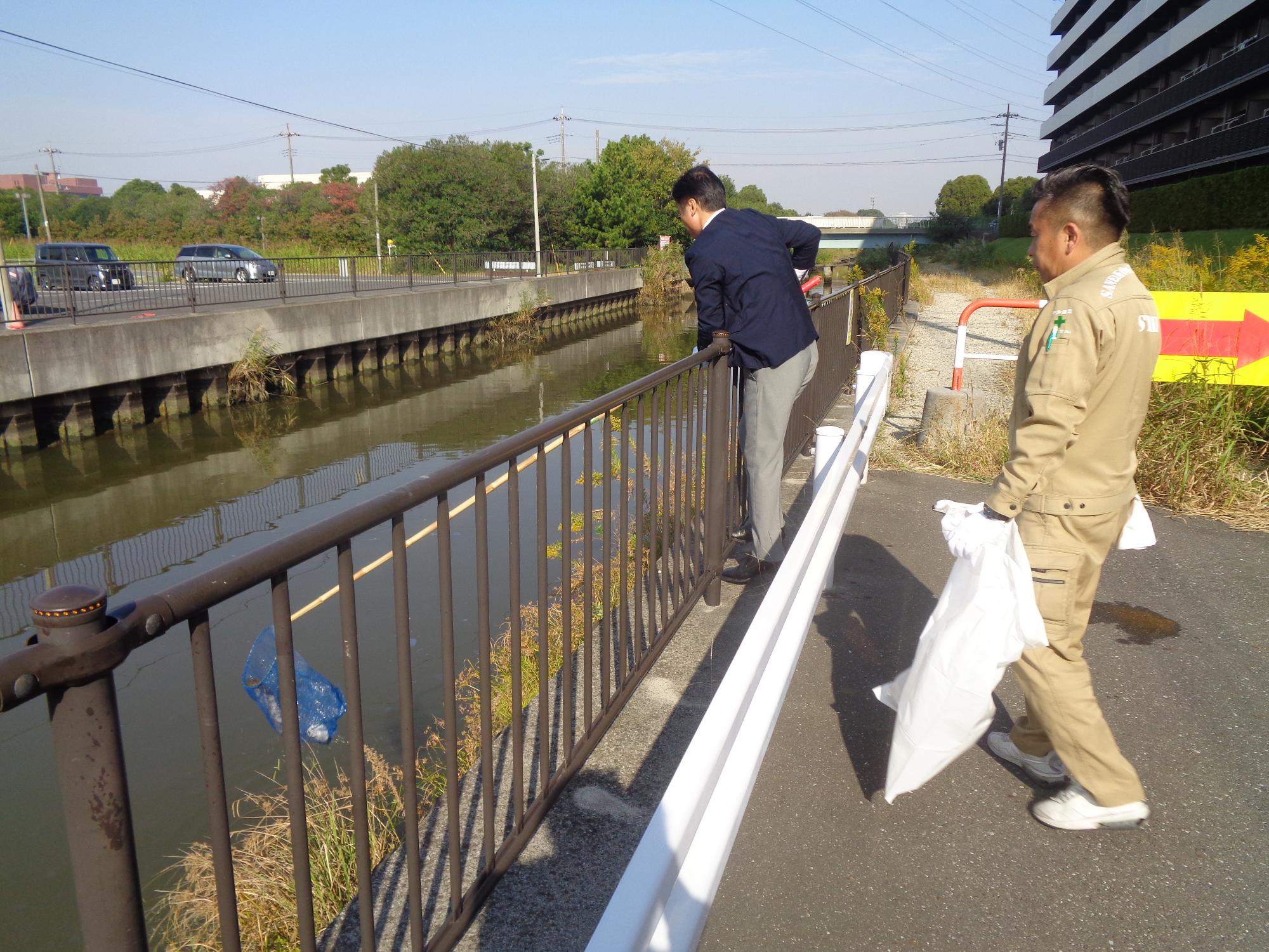 川に浮遊しているごみを網を使って拾っている写真