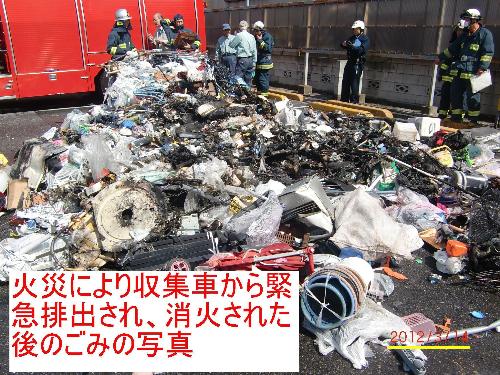 火災により収集車から緊急排出され、消火された後のごみの周りに消防隊員が集まり調査している写真