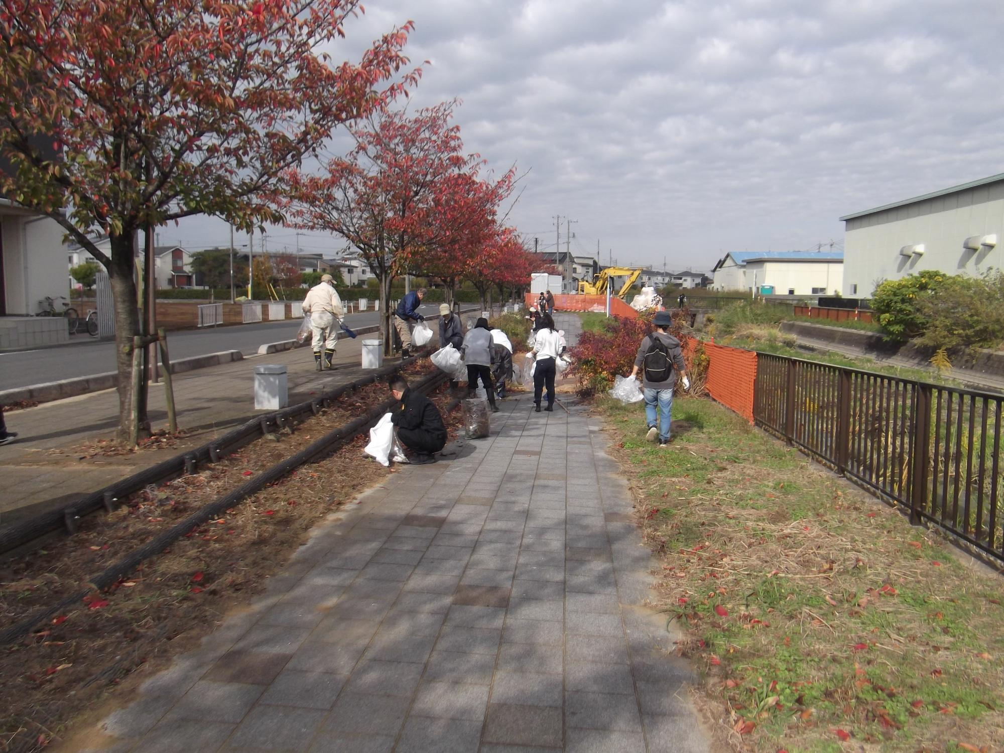 川沿いで浮遊ゴミをすくうための網を持っている人達の写真