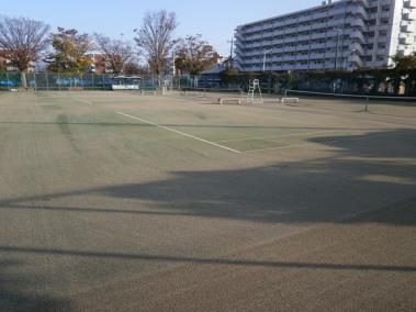 広々とした敷地に、砂入り人工芝のテニスコートが並んでいる写真