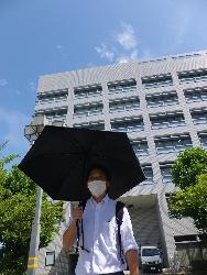 日傘を差しながら歩く男性の写真