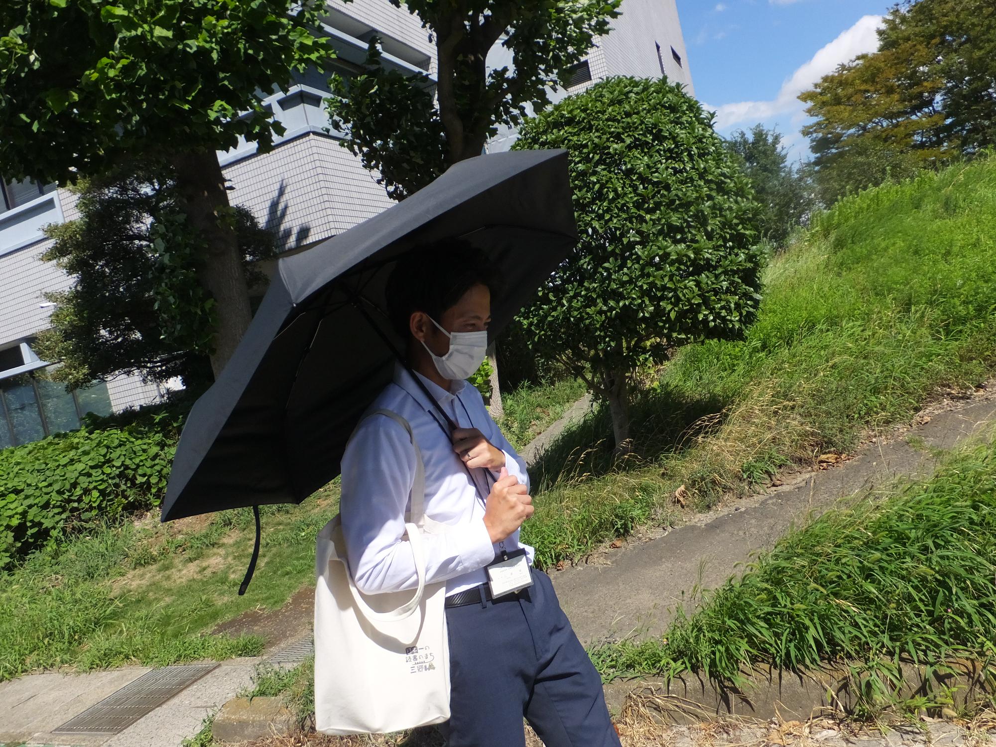 日傘を差して歩行する男性