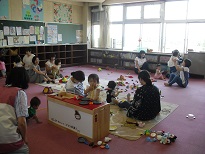 ピンクの床に座り遊んでいる数組の参加者親子を写したばんびサロンの写真