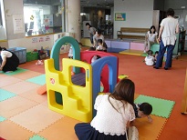 カラフルな遊具が中央に置かれ、数組の親子が遊んでいるひよこサロンの様子を写した写真