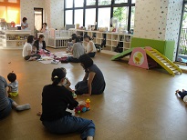 広い室内に玩具や遊具があり、子どもとお母さんが一緒に遊んでいる写真