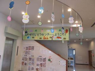 早稲田児童センター 正面入り口 天井から様々なオブジェがつるされている 児童センターへようこその看板